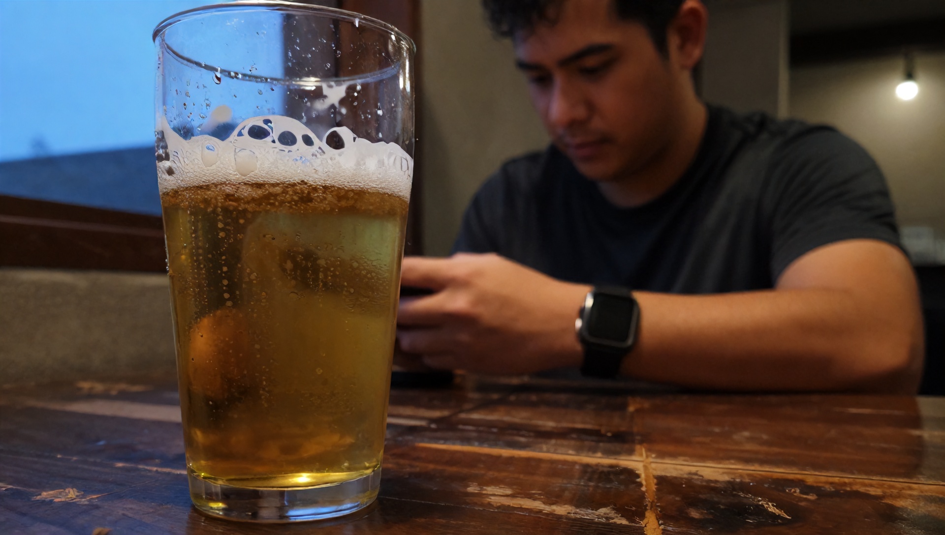 Homem analisando copo de cerveja e pensando na recuperação muscular